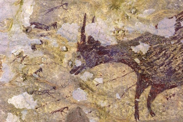 Pittura rupestre che mostra un anoa di pianura circondato da piccole figure antropomorfe. Credit: Adam Brumm / Ratno Sardi